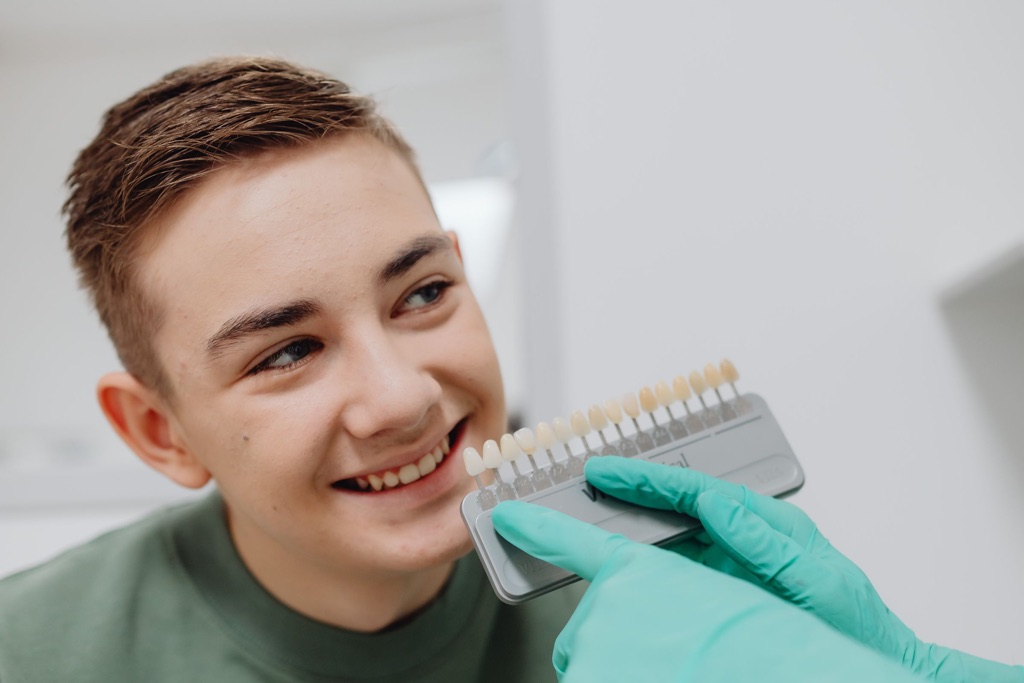 Paciente sonriendo mientras la dentista compara el color de sus dientes con una guía de colores